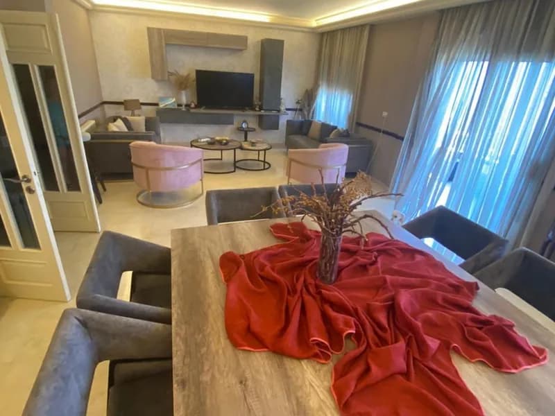Renovated salon and dining area of the Ballouneh apartment, with cove lighting and a large dining table