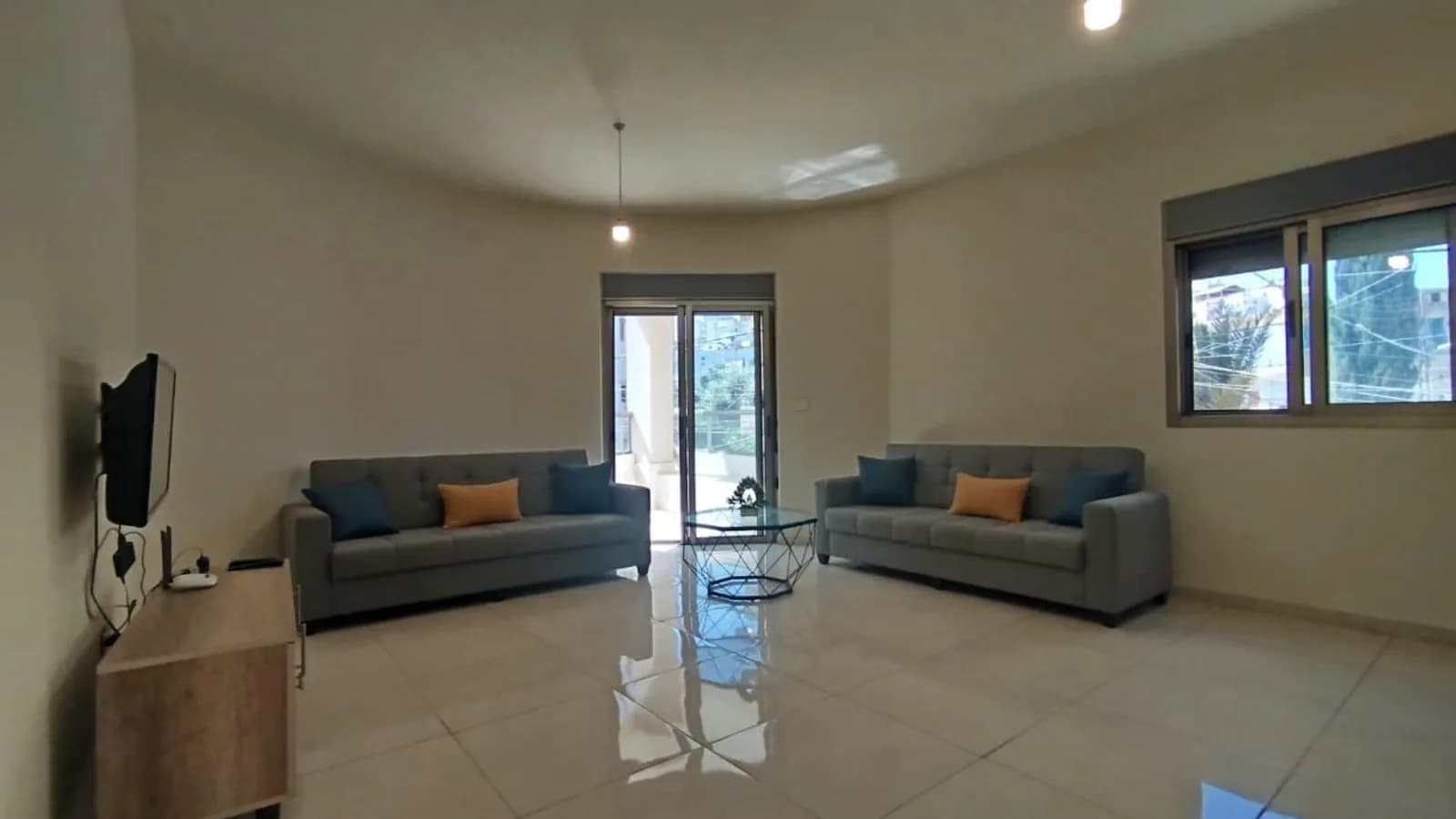 Salon of the Sarba apartment with two sofas, television and balcony doors