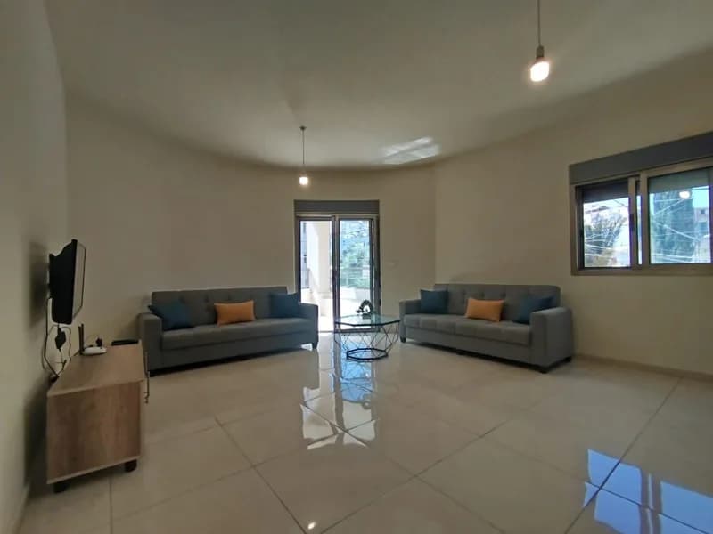 Salon of the Sarba apartment with two sofas, television and balcony doors